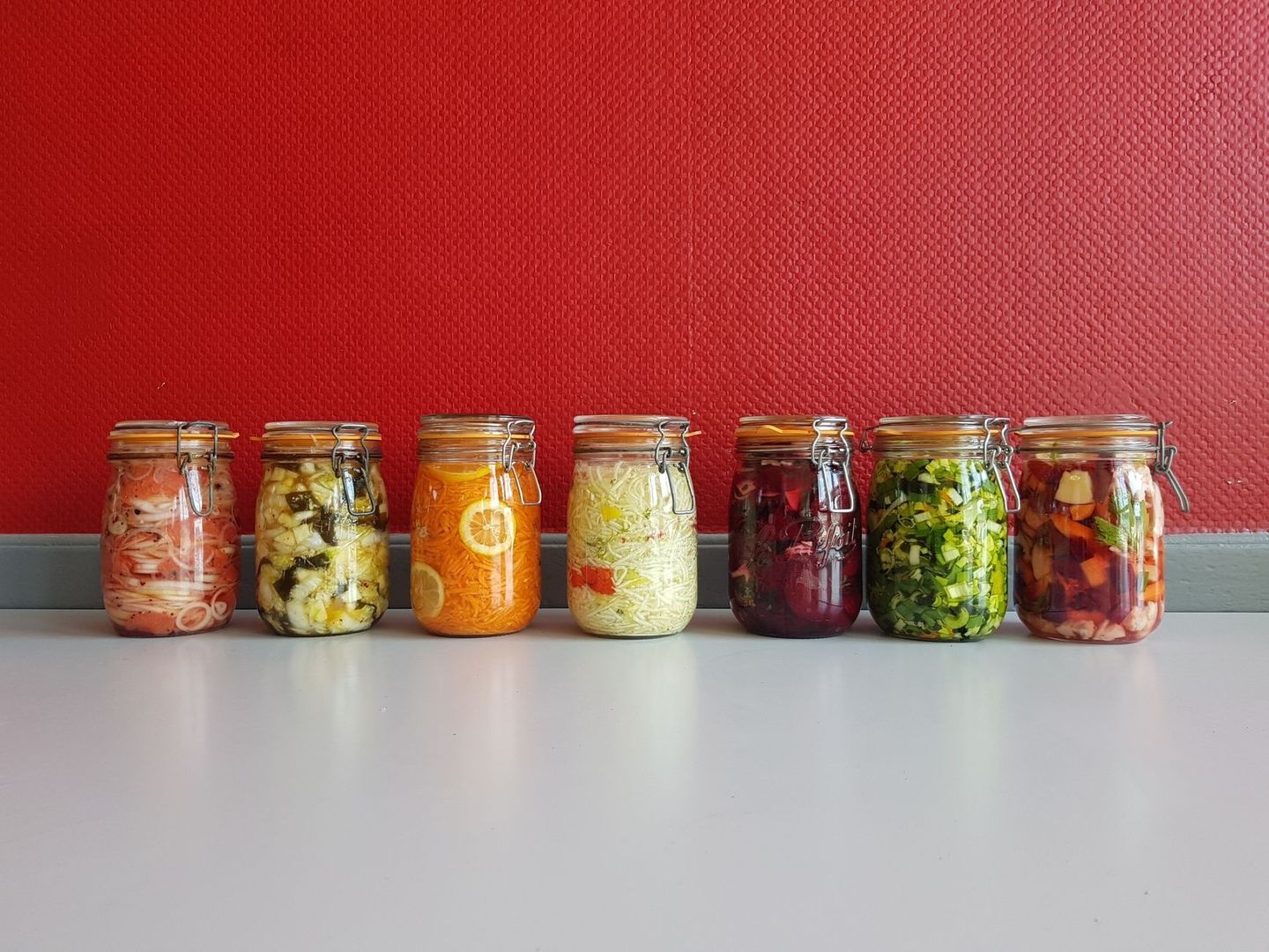 Sieben Bügelgläser mit bunt eingelegtem Gemüse als Fermentationsauswahl